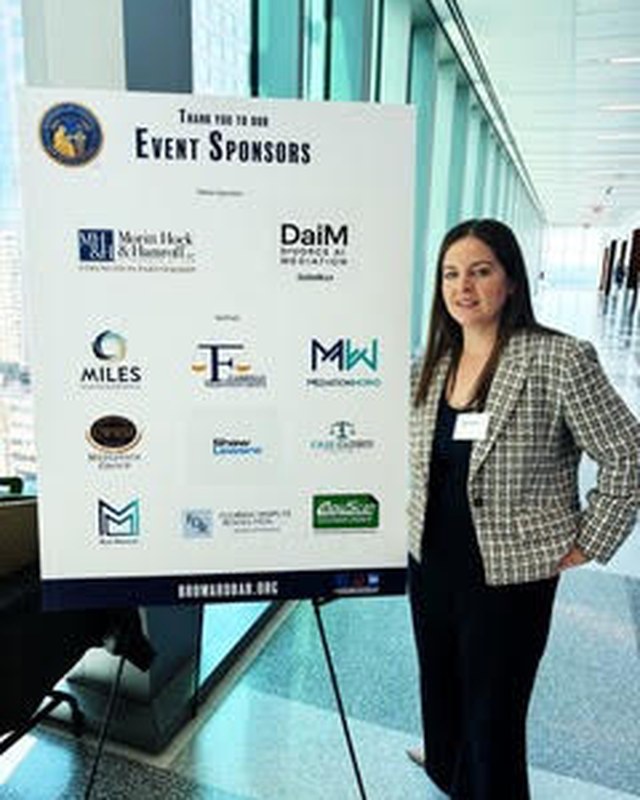 Katie standing beside a Broward Bar event sponsor display.